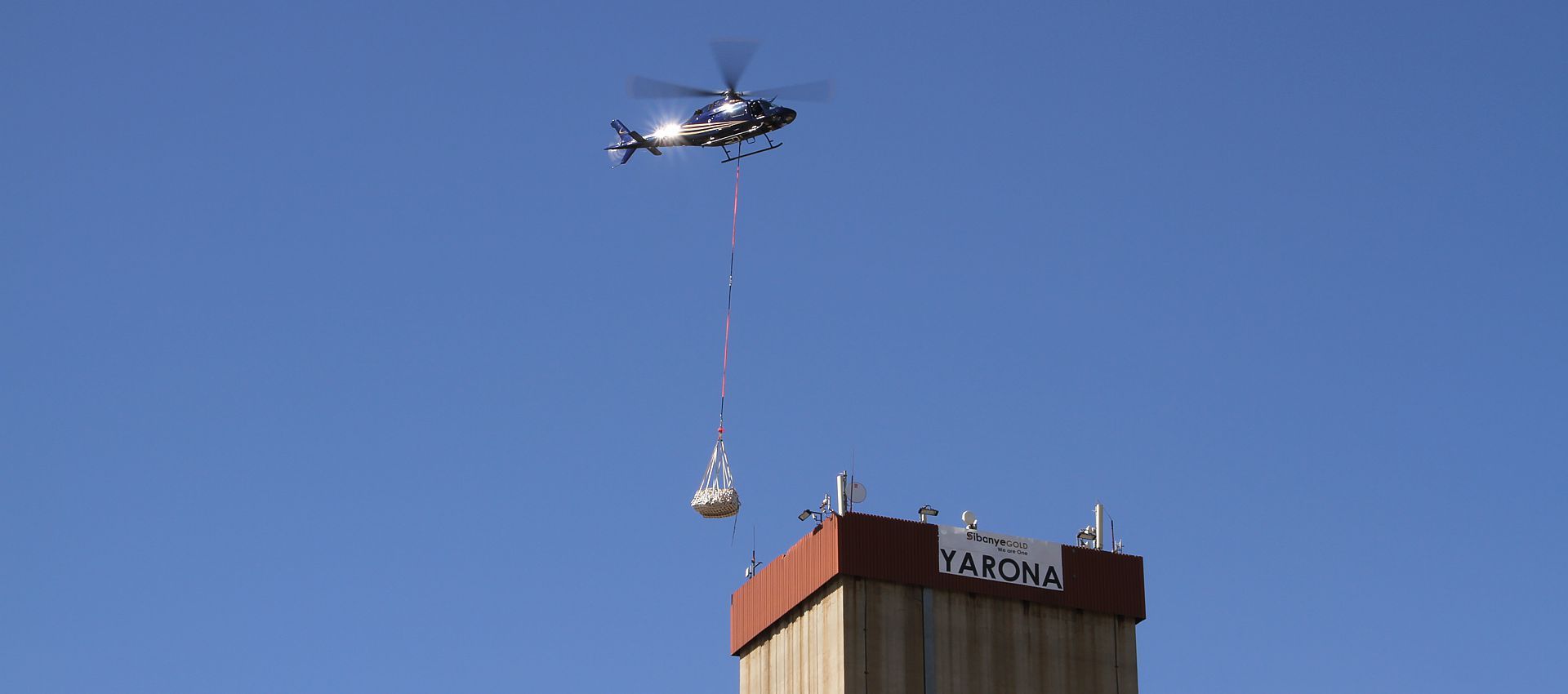 Agusta 119ke ZS-HRV lifting telecoms equipment onto the top of a mine shaft